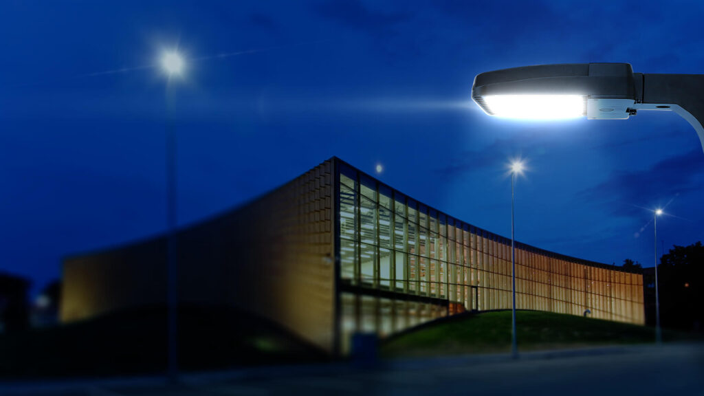 A commercial building illuminated by Greenlogic LED lighting solutions, with a focus on a prominent LED area light in the foreground.