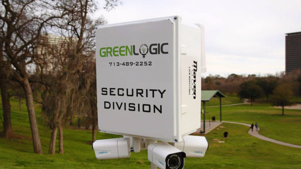 An image of a Greenlogic surveillance system with various types of security cameras installed on a pole, providing security to a public park in the background.