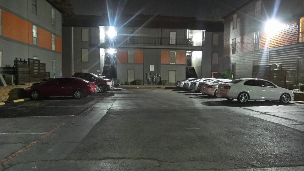 Well-illuminated parking lot with parked cars, showcasing the effectiveness of property management LED lighting.