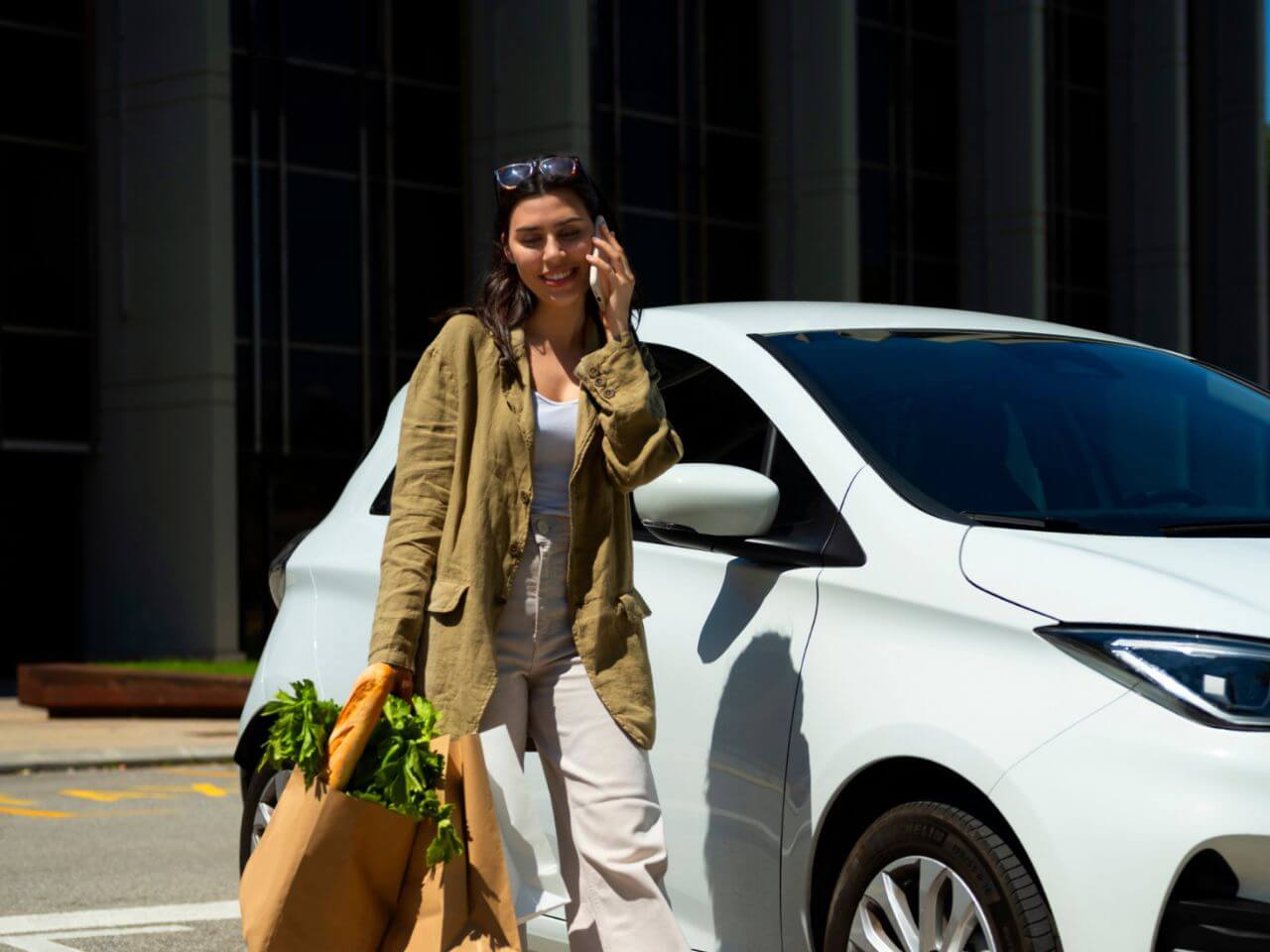 Woman with shopping bags approaching her charged EV at a retail parking lot, highlighting the convenience of EV charging retail solutions.